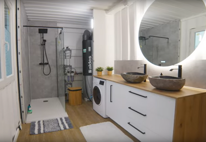 Une salle de bain aménagée dans une maison container, avec une double vasque. Source : chaine YouTube de Julien Malara
