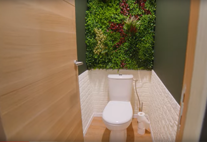 Toilettes aménagées dans une maison container, avec un mur végétal artificiel. Source : chaine YouTube de Julien Malara